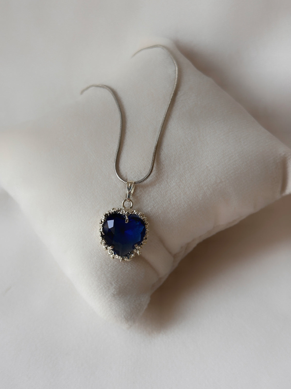 Heart-shaped blue pendant on a white cushion